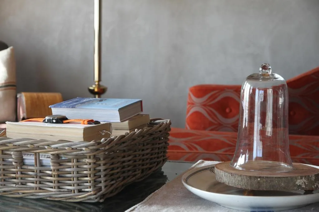 Decorative room details with wicker basket, books, glass cloche, and red cushion