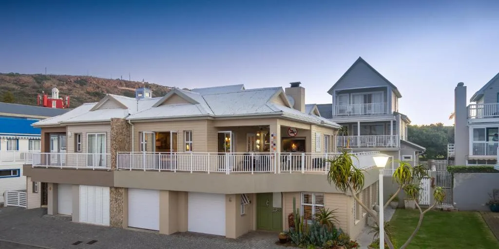 Beige holiday home with wraparound deck and garages, hillside setting