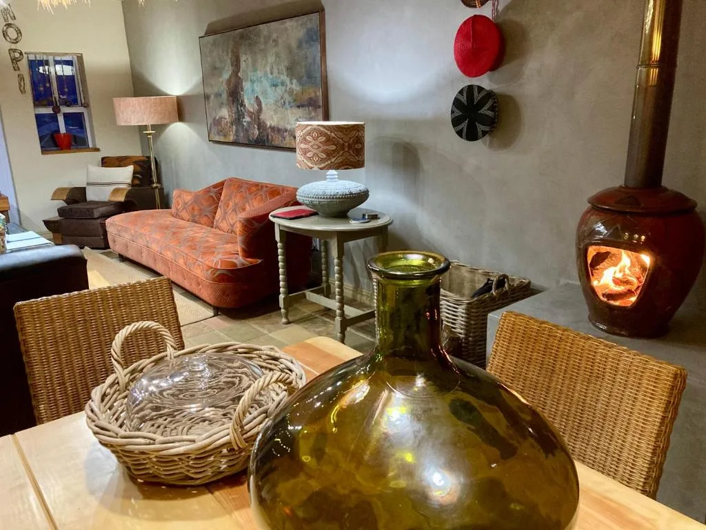 Cozy lounge with orange sofa, wood stove fireplace, and eclectic decor