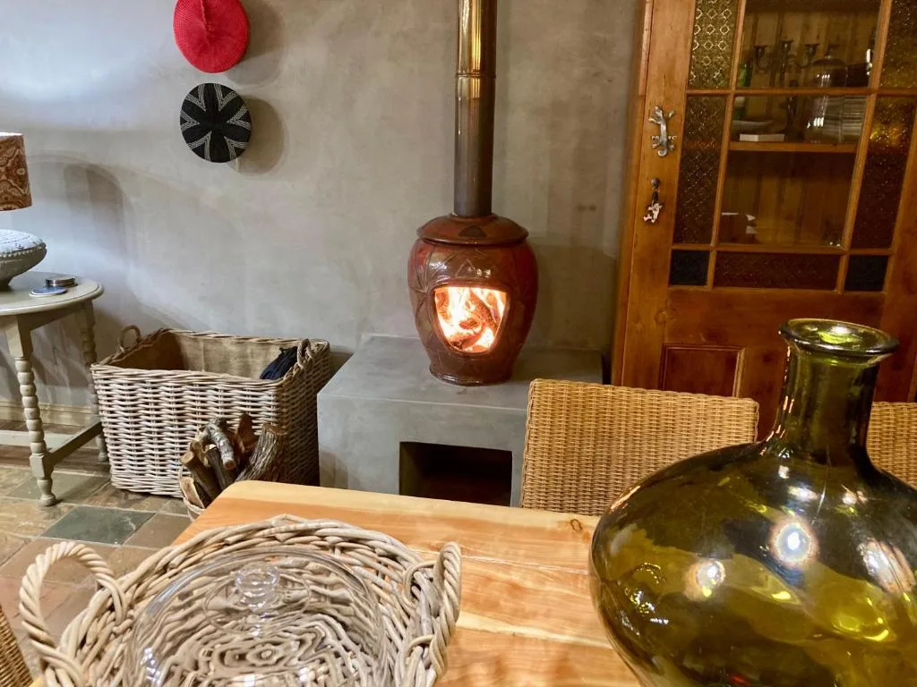 Cozy lounge with decorative fireplace, wicker chairs, and wooden cabinets