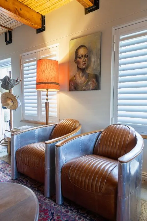 Modern lounge with brown leather armchairs, portrait artwork, and orange lamp