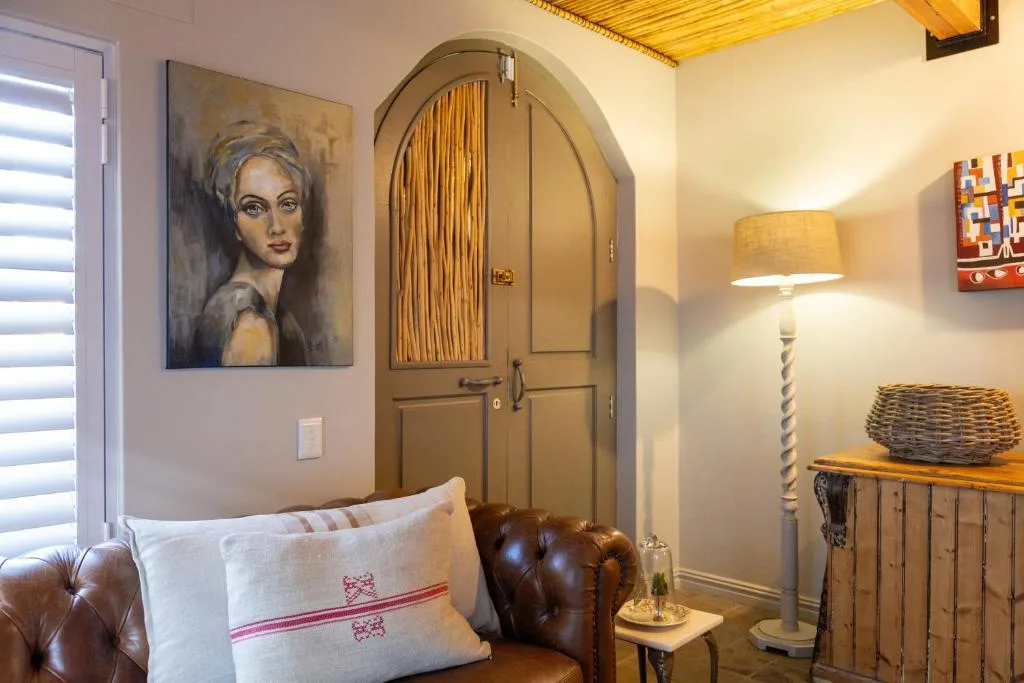 Cozy lounge with leather sofa, portrait artwork, arched wardrobe door, and warm lighting