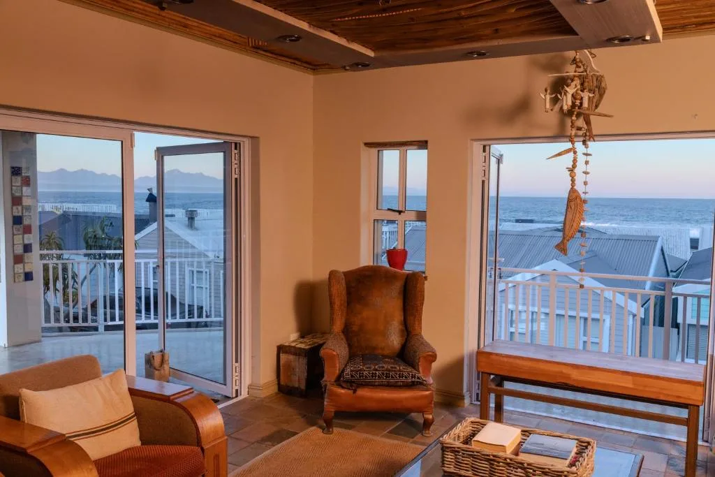 Spacious lounge with leather armchair overlooking ocean and mountains through glass doors