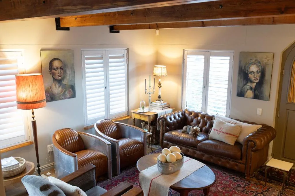 Elegant living room with leather sofa, armchairs, exposed beams, and artwork