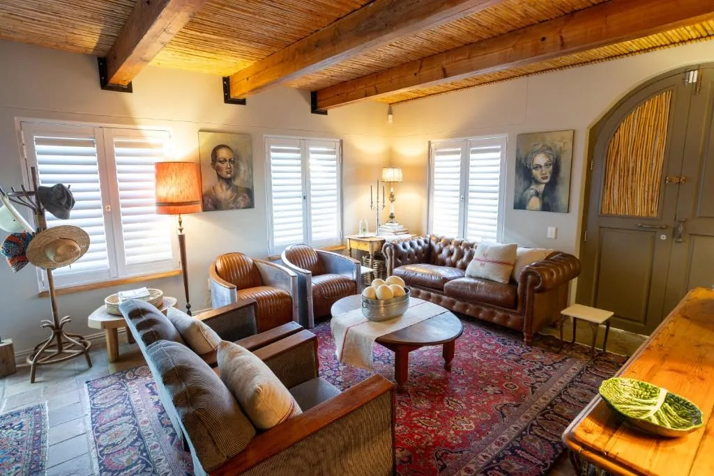 Spacious lounge with leather sofas, wooden beams, and warm lighting