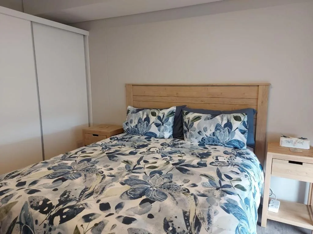 Bright bedroom with wooden bed frame and patterned blue floral bedding