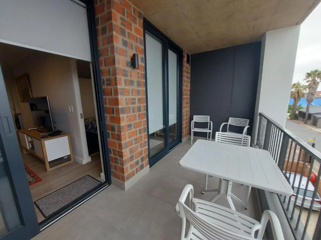 Modern balcony with white furniture and ocean view access doors