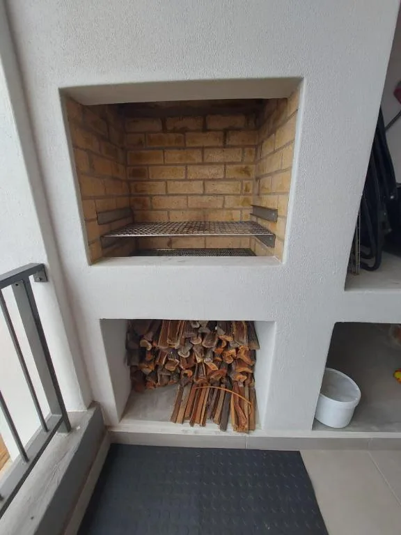 Built-in fireplace with brick interior and stacked firewood storage below