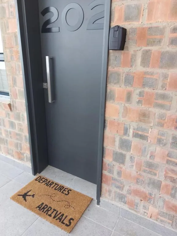 Modern dark door entrance with brick facade and welcoming doormat