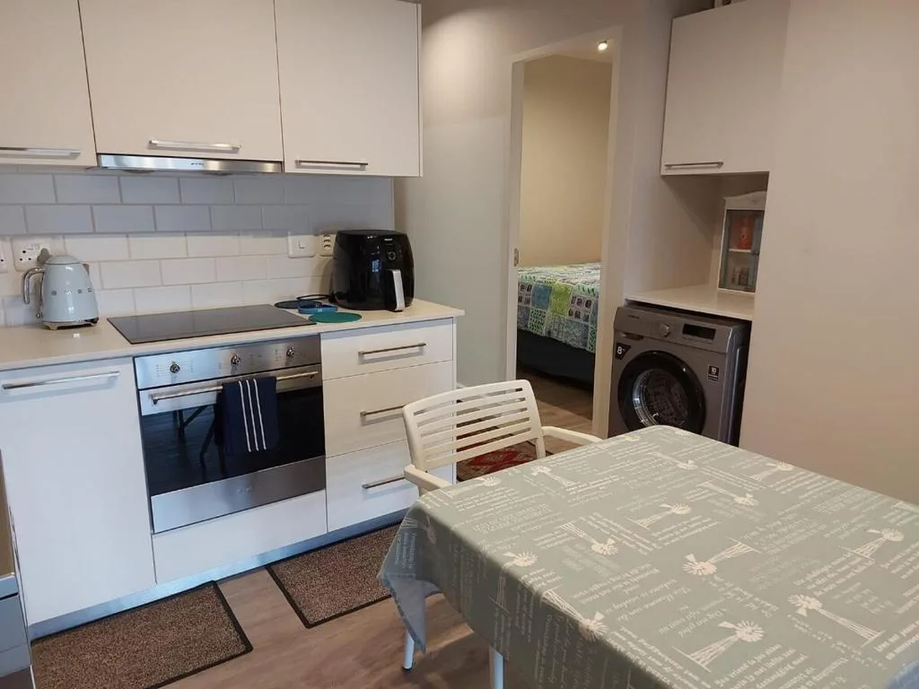Modern kitchen with white cabinetry, stainless steel appliances, and dining table