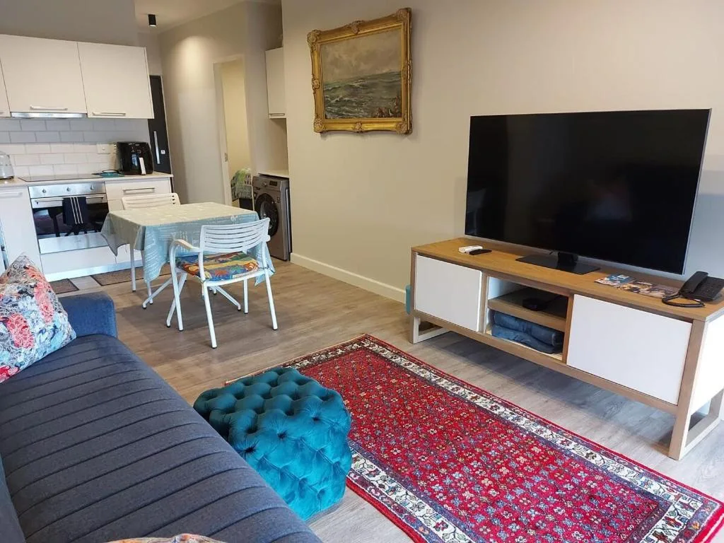 Open-plan living area with sofa, TV, and integrated kitchen in background