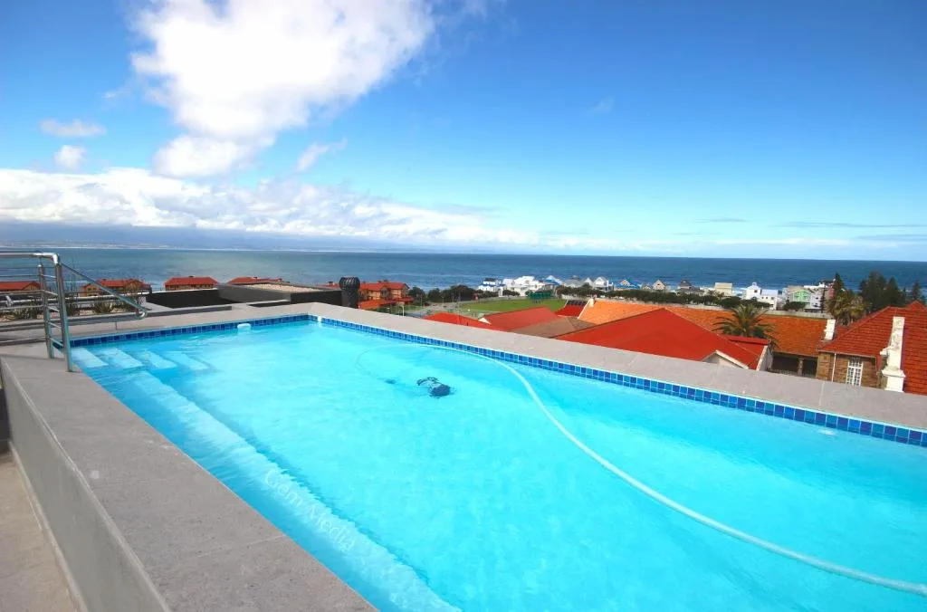 Bright blue swimming pool overlooking Mossel Bay and ocean coastline