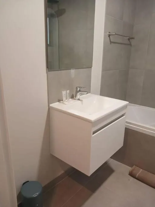 Modern bathroom with white vanity, mirror, and walk-in shower enclosure