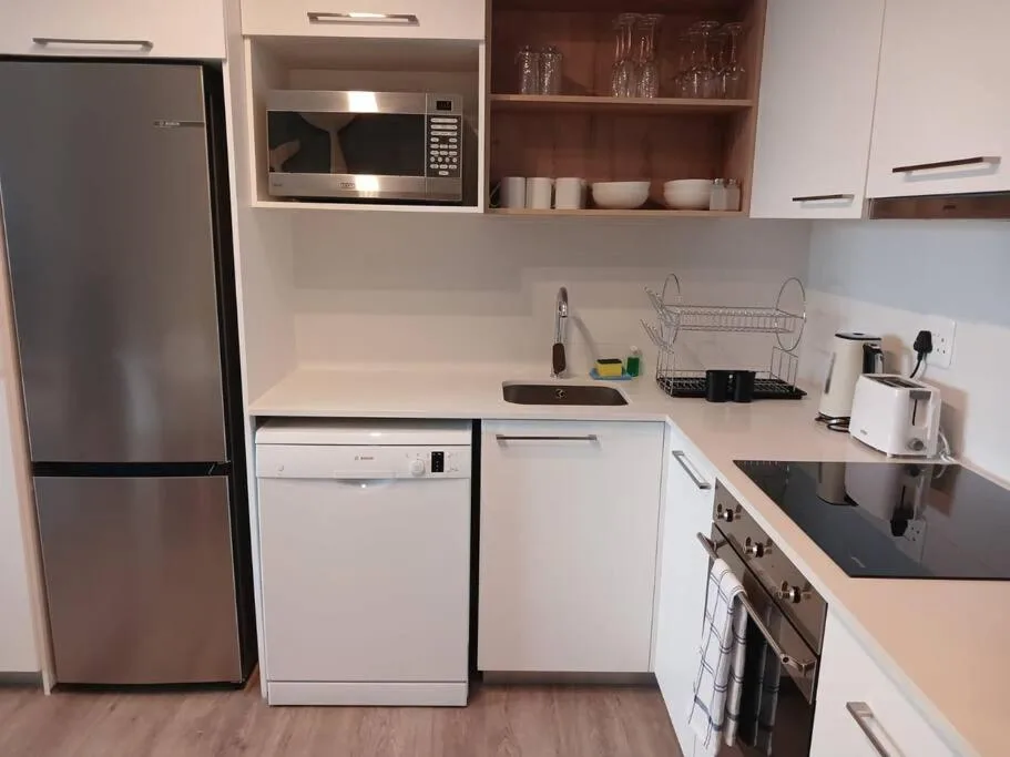 Modern kitchen with stainless steel appliances, white cabinetry, and open shelving