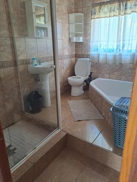 Bathroom with shower enclosure, toilet, pedestal sink, and bathtub with mat