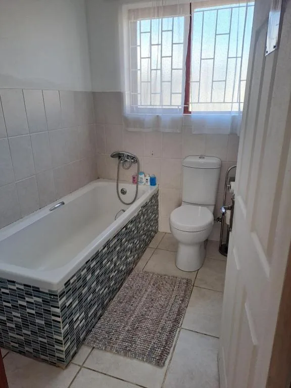 Bathroom with bathtub, toilet, and window with natural light
