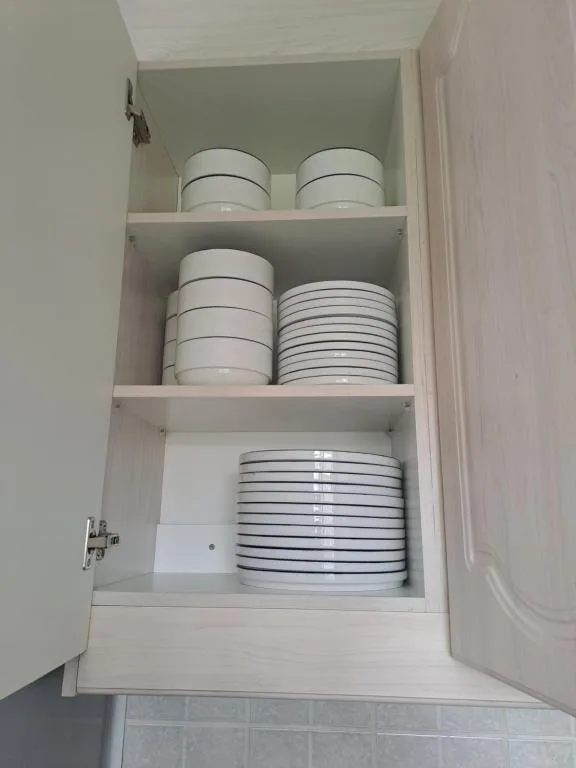 Open kitchen cabinet displaying neatly stacked white dinnerware and plates