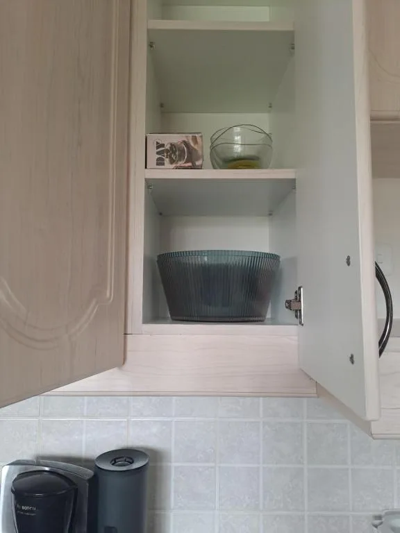 Open kitchen cabinet displaying glassware and decorative items neatly arranged