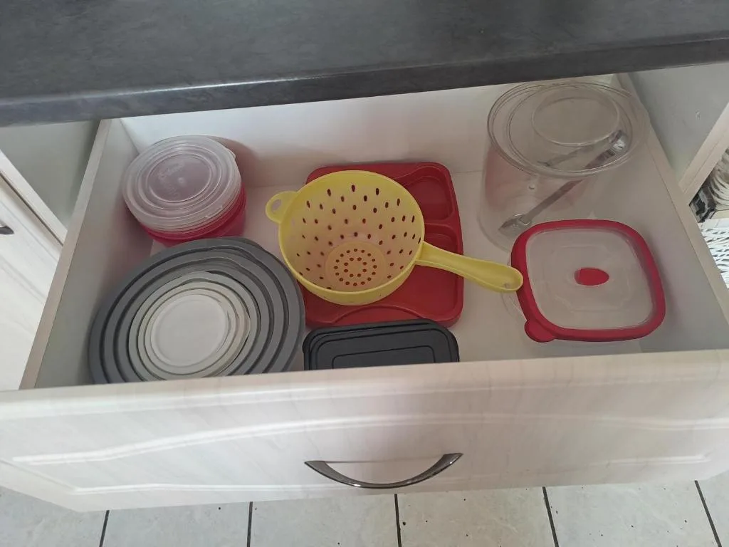 Kitchen drawer with organized cookware and storage containers neatly arranged