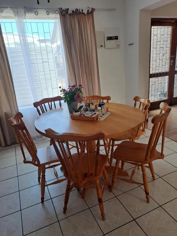 Round wooden dining table with chairs and floral centerpiece arrangement