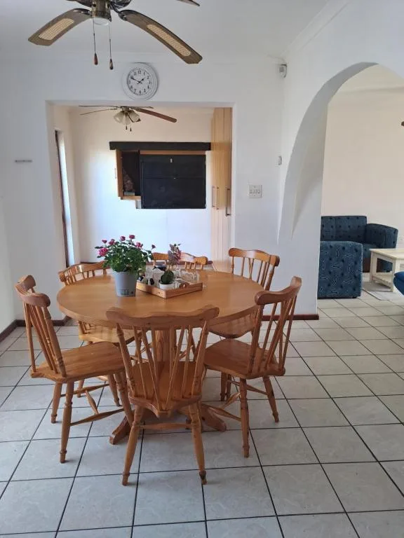 Wooden round dining table with chairs and fresh flowers centerpiece