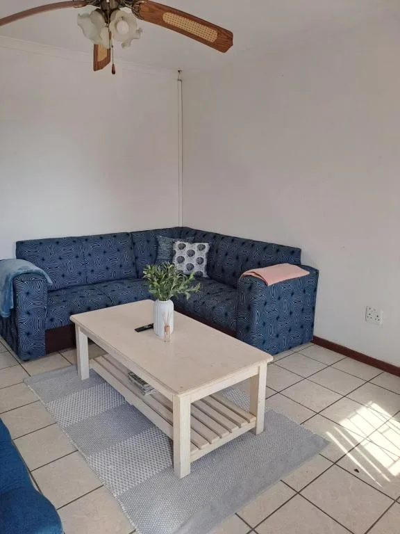Blue patterned corner sofa with white coffee table and ceiling fan