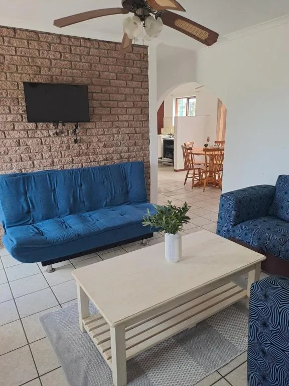 Open-plan lounge with blue sofa, armchair, and white coffee table