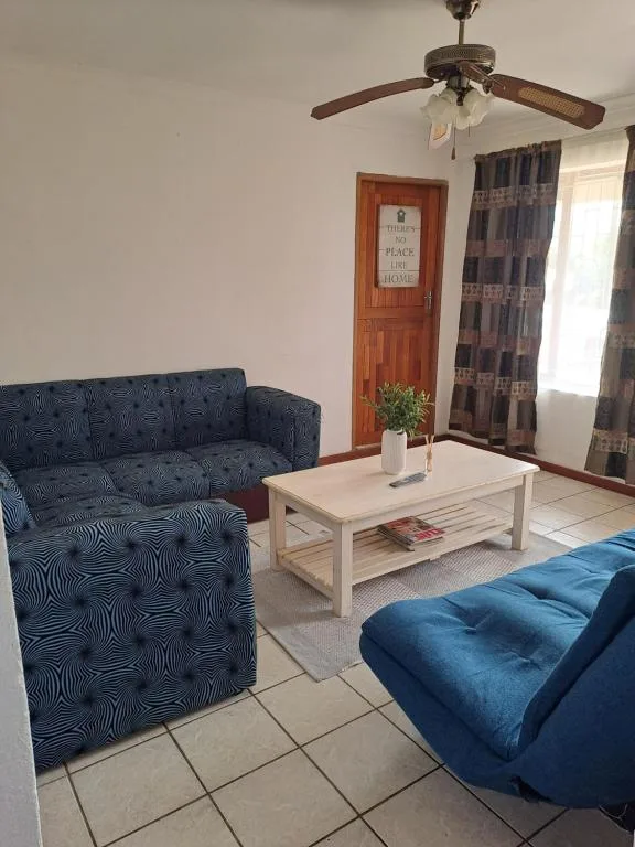 Living room with blue patterned sofa, white coffee table, ceiling fan