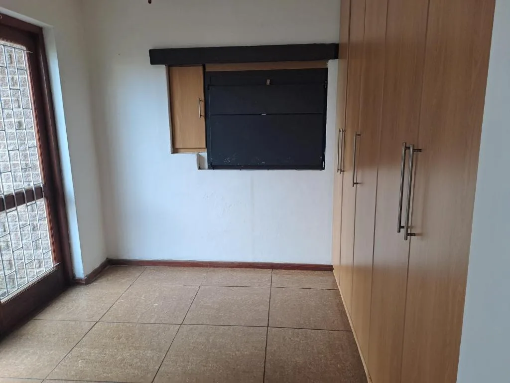 Spacious lounge with wall-mounted TV and wooden built-in cupboards