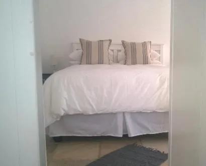 Neatly made bed with white linens and striped accent pillows in bedroom