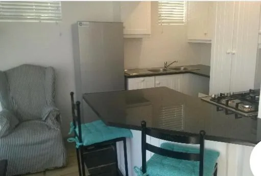 Open-plan kitchen with black countertops, stove, and refrigerator visible