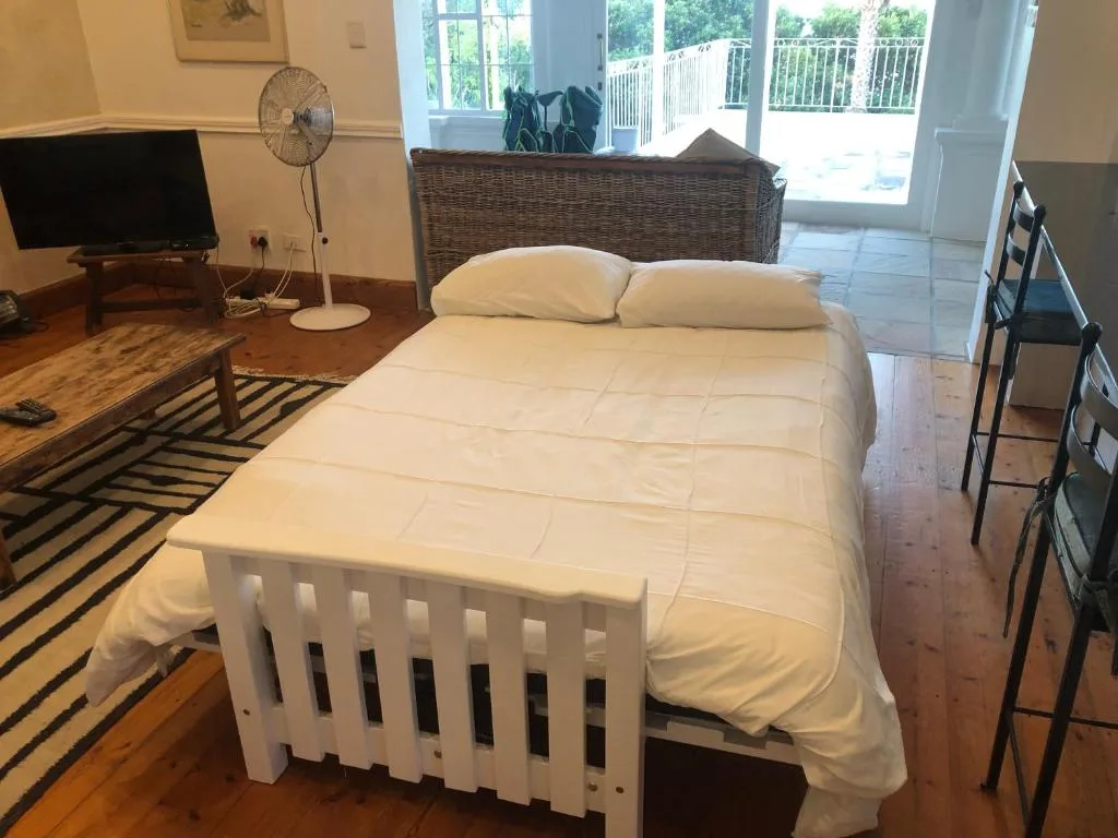Spacious bedroom with white bed, TV, and access to deck beyond