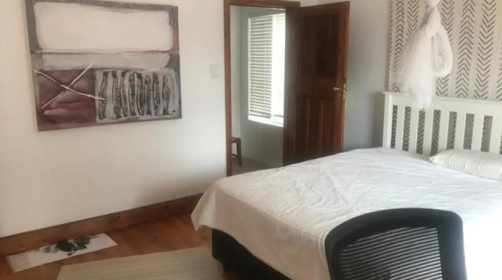 Spacious bedroom with white bedding, wooden headboard, and wall art