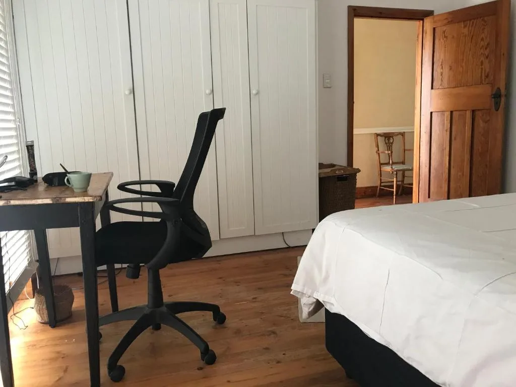 Spacious bedroom with double bed, desk, office chair, and wooden flooring