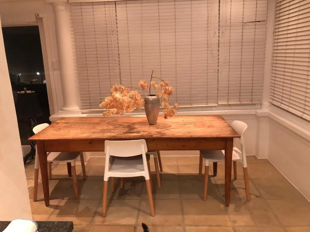 Wooden dining table with white chairs and dried flower centerpiece