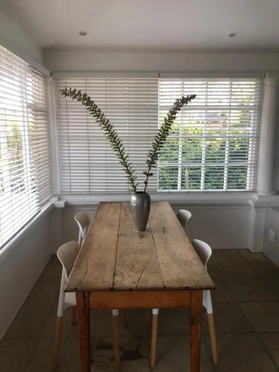 Rustic wooden dining table with white chairs and plant arrangement