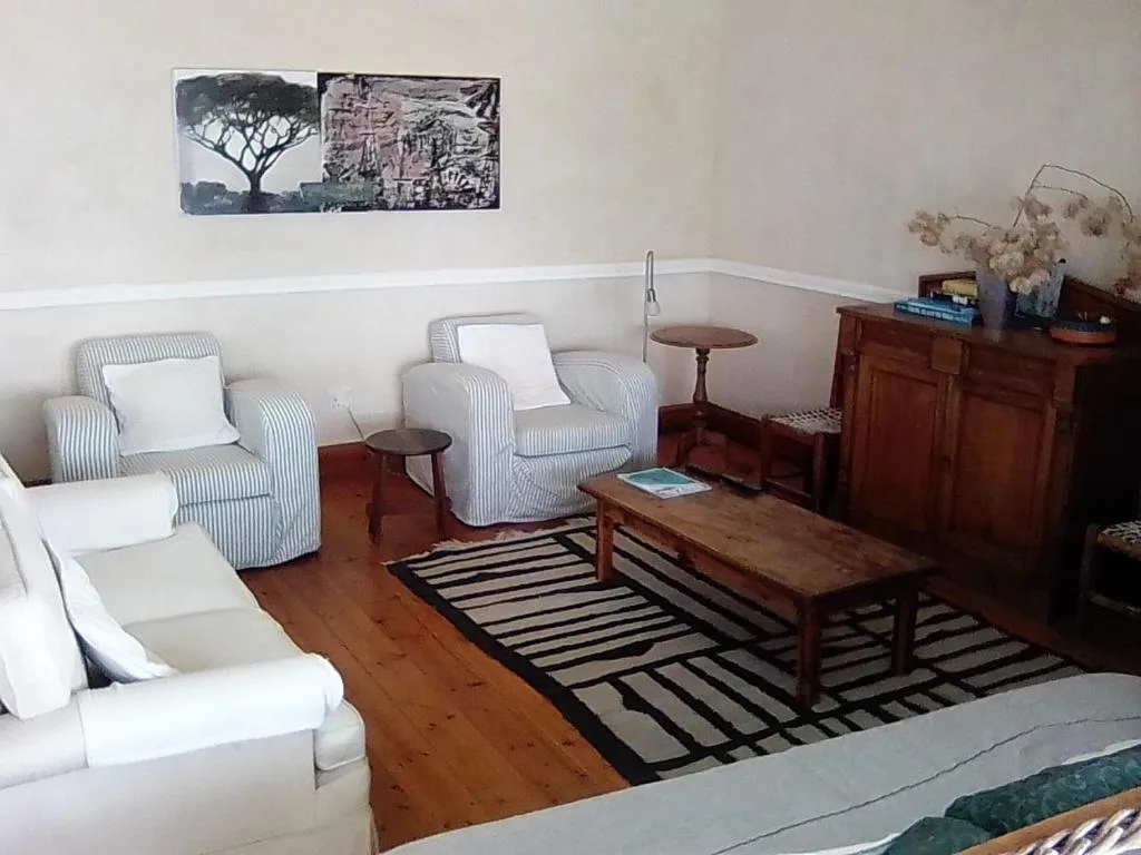 Spacious lounge with striped armchairs, wooden furniture, and wall art