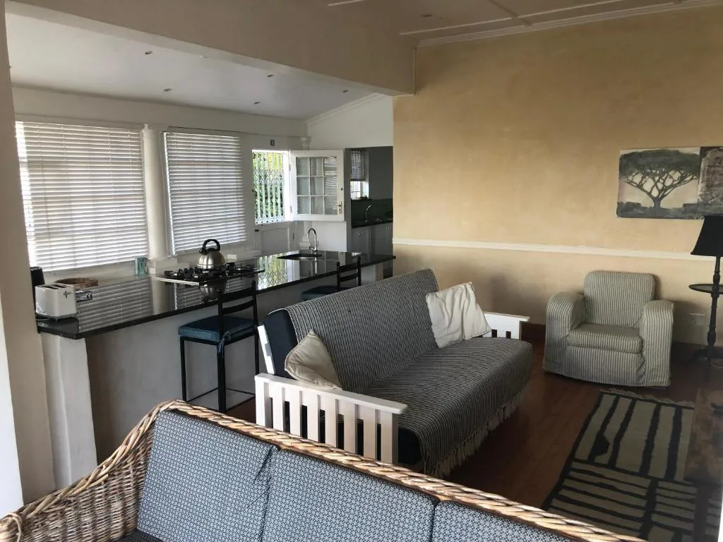 Open-plan lounge and kitchen with sofa, armchair, and dining counter seating