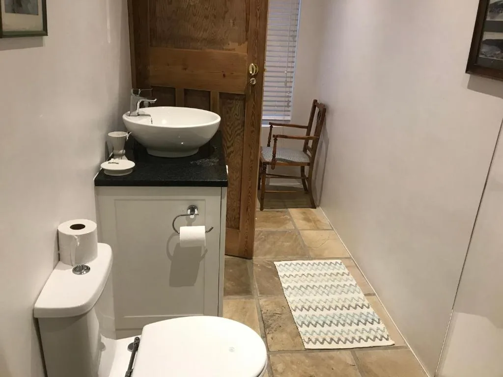 Modern bathroom with round vessel sink, toilet, and stone countertop