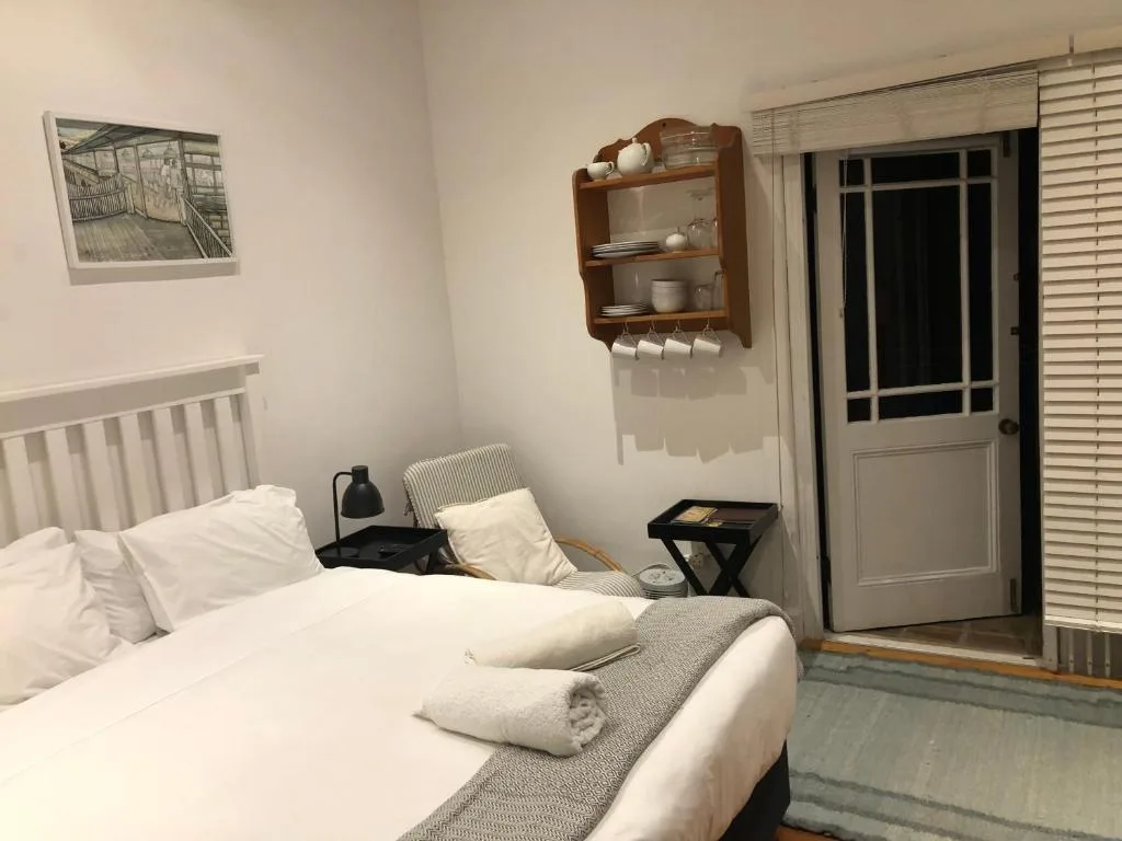 Bright bedroom with white bed, wooden shelf, and glass door to patio