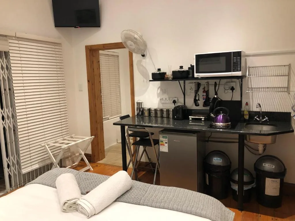 Studio bedroom with kitchenette, bed with rolled towels, wall-mounted TV