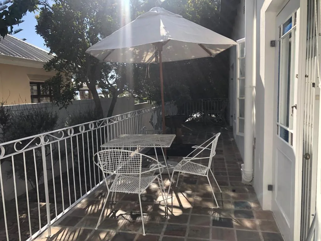 Shaded patio with umbrella, dining table, and chairs overlooking garden