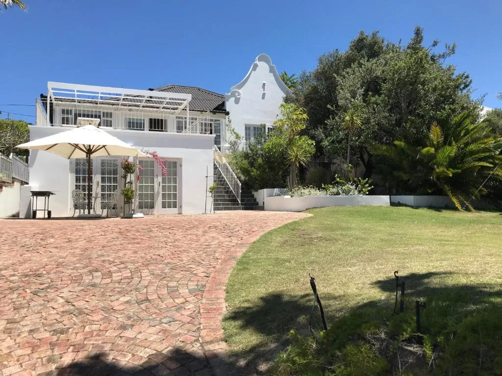 White Cape Dutch cottage with manicured garden and brick patio area