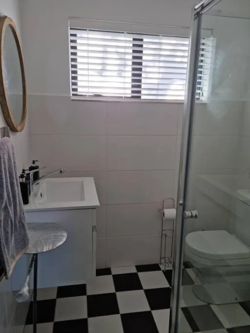 Clean bathroom with white vanity, toilet, and geometric black-and-white floor tiles