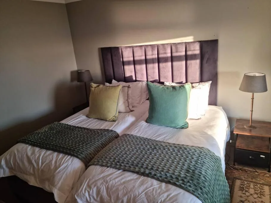 Comfortable bedroom with double bed, colorful pillows, and bedside lamps