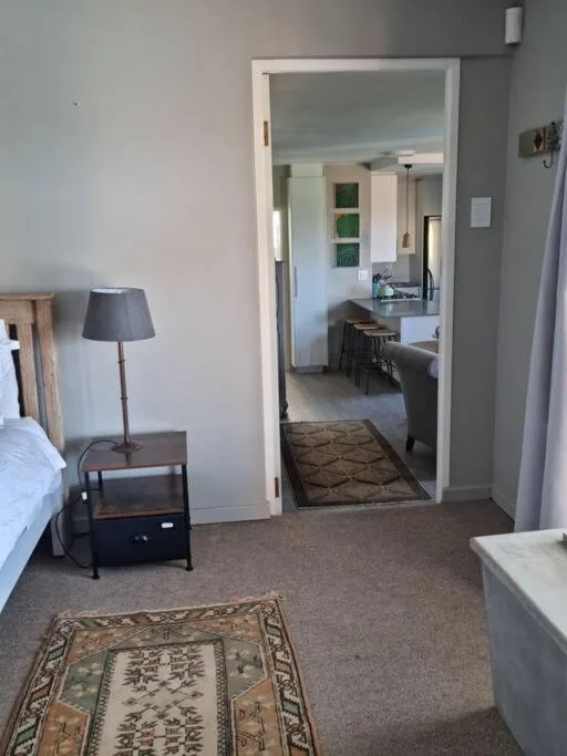 Bedroom with bed, bedside table, lamp, open doorway to kitchen area