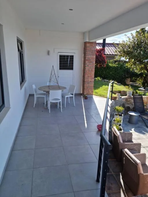 Covered patio with dining table, chairs, and garden views beyond