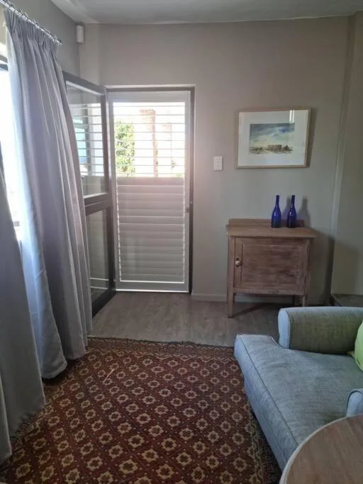 Light-filled lounge with sofa, wooden cabinet, and glass door to patio