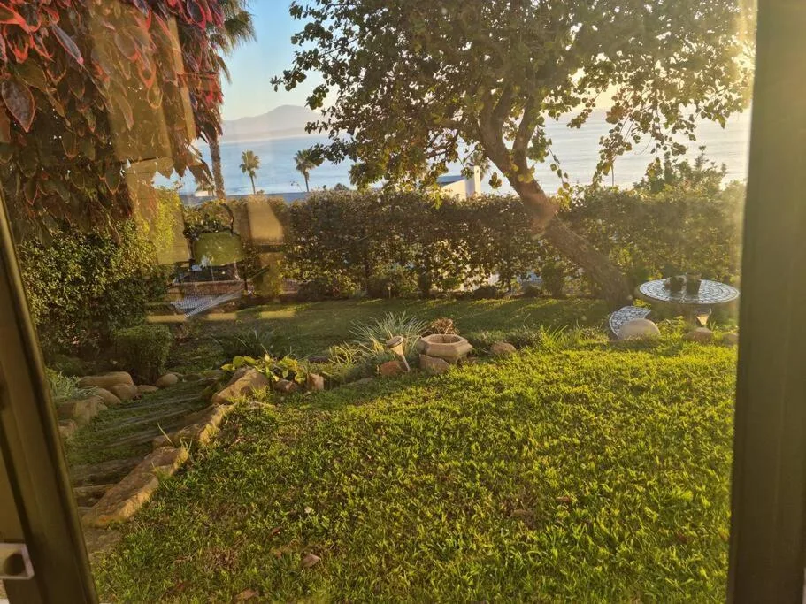 Lush garden with distant ocean and mountain vista beyond hedges