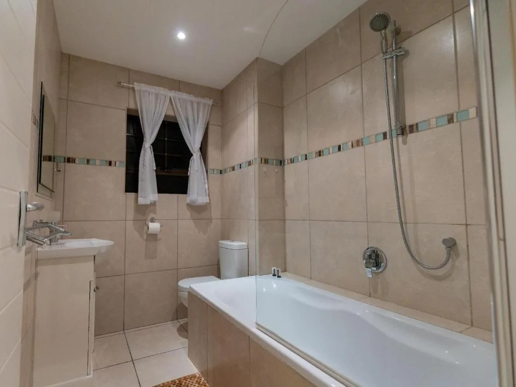 Spacious bathroom with bathtub, shower, sink, and decorative tile accents